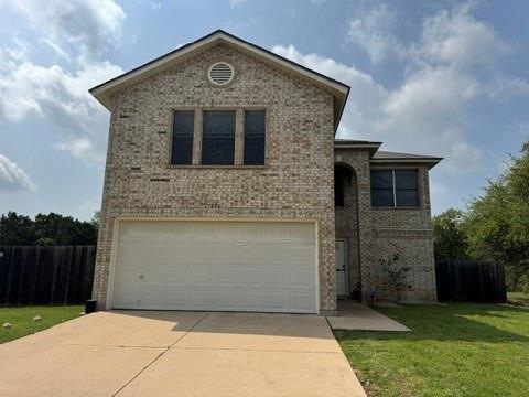 Traditional-style house with fence, driveway, a front yard, brick siding, and a garage