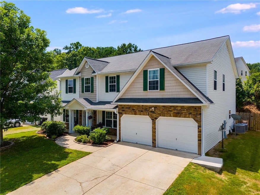 View of front of home with concrete driveway, stone siding, a garage, and roof with shingles