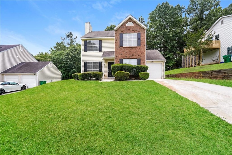 View of front of property with a front lawn, concrete driveway, a chimney, and brick siding