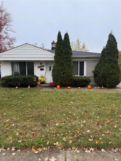 View of front of house featuring a front yard, a chimney, and brick siding
