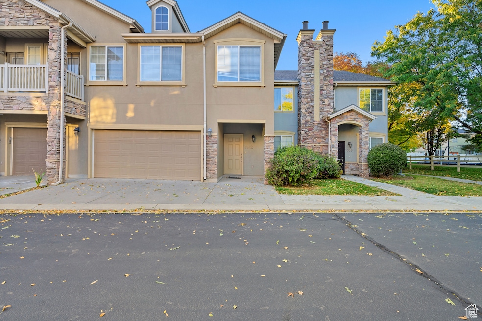Traditional home with stucco siding, concrete driveway, stone siding, a garage, and a chimney