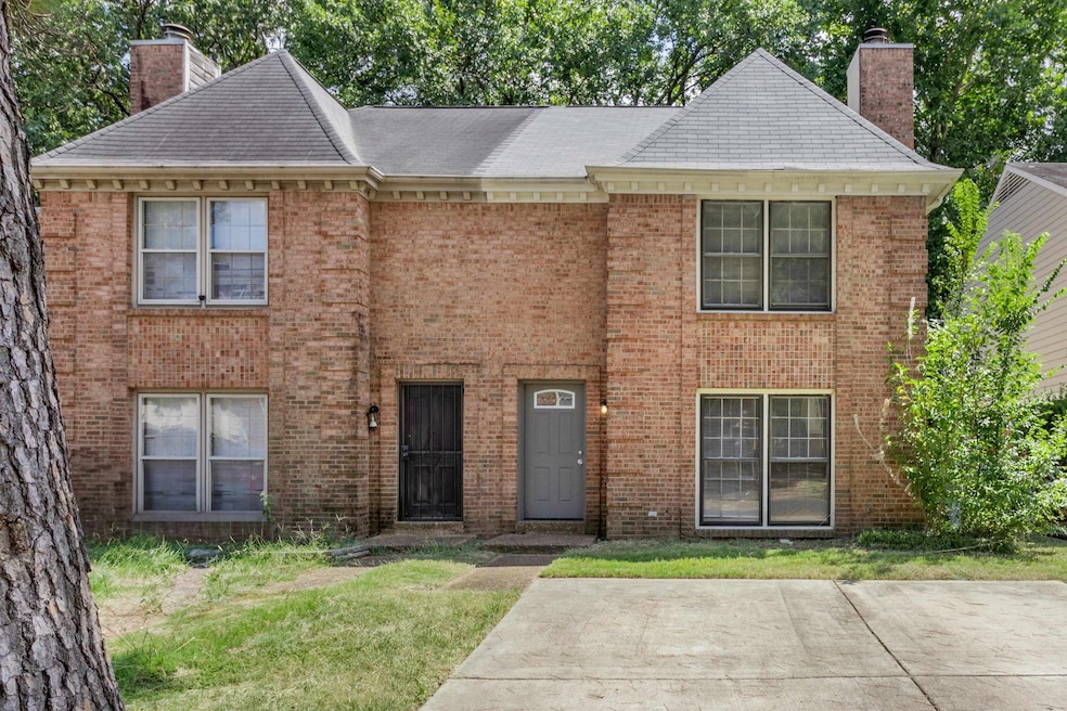 View of front of property with a chimney, brick siding, and a front lawn