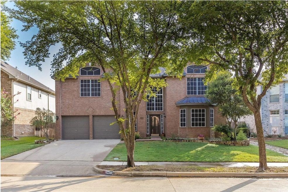 View of front of home with a front yard, brick siding, concrete driveway, and an attached garage