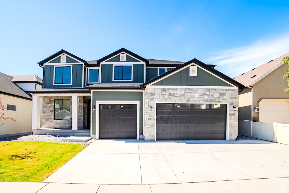 View of front of house featuring stone siding, board and batten siding, driveway, and covered porch