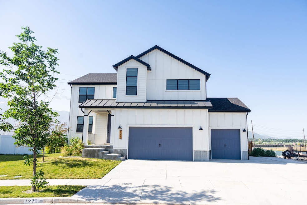 Modern farmhouse style home featuring board and batten siding, a standing seam roof, driveway, and a front lawn