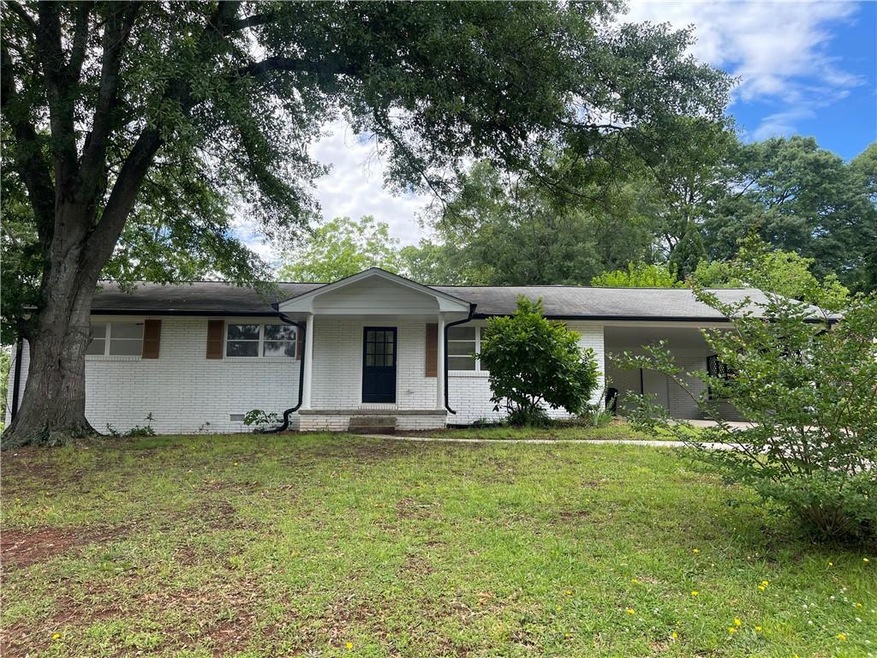 Ranch-style home with a front lawn, brick siding, an attached carport, a porch, and crawl space