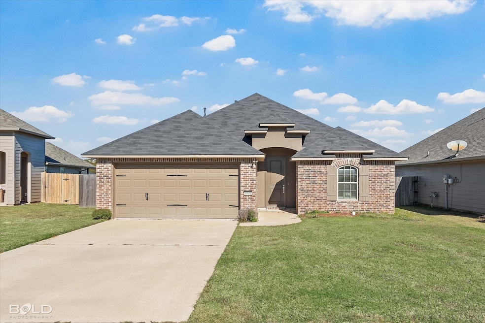 French country style house with concrete driveway, brick siding, roof with shingles, and an attached garage