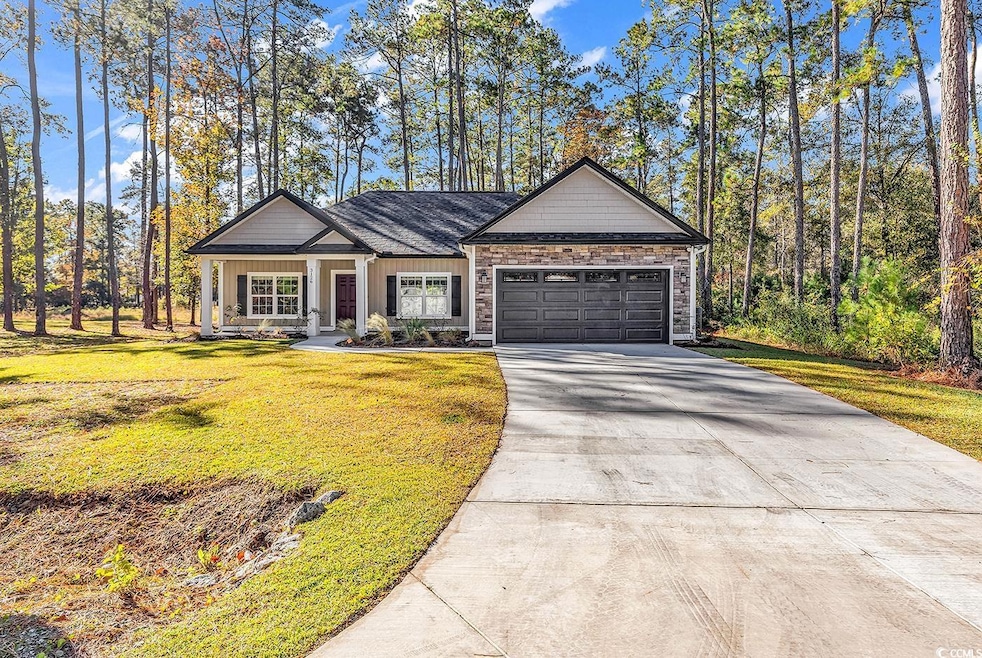 View of front of property with driveway, a front yard, an attached garage, board and batten siding, and covered porch
