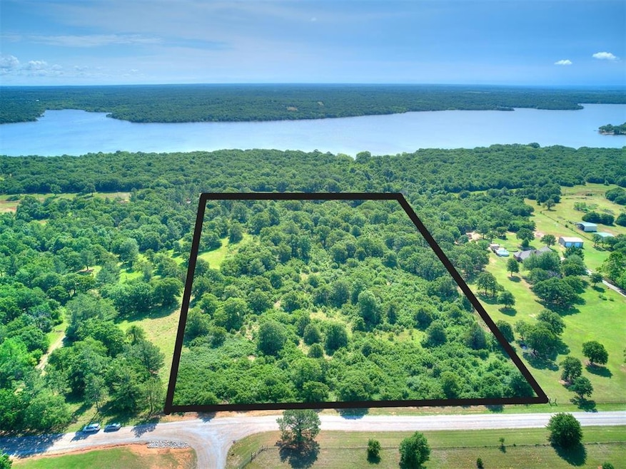 Aerial view of property and surrounding area with a large body of water, a heavily wooded area, and property parcel outlined