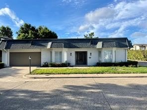 View of front facade featuring mansard roof, driveway, and an attached garage