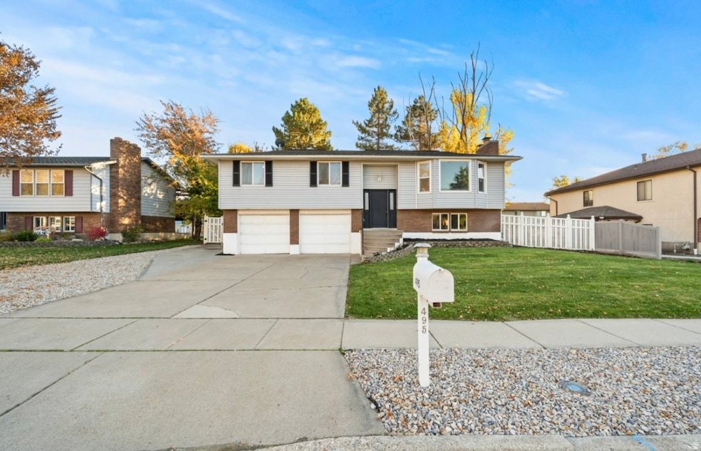 Split foyer home featuring brick siding, driveway, a chimney, and an attached garage