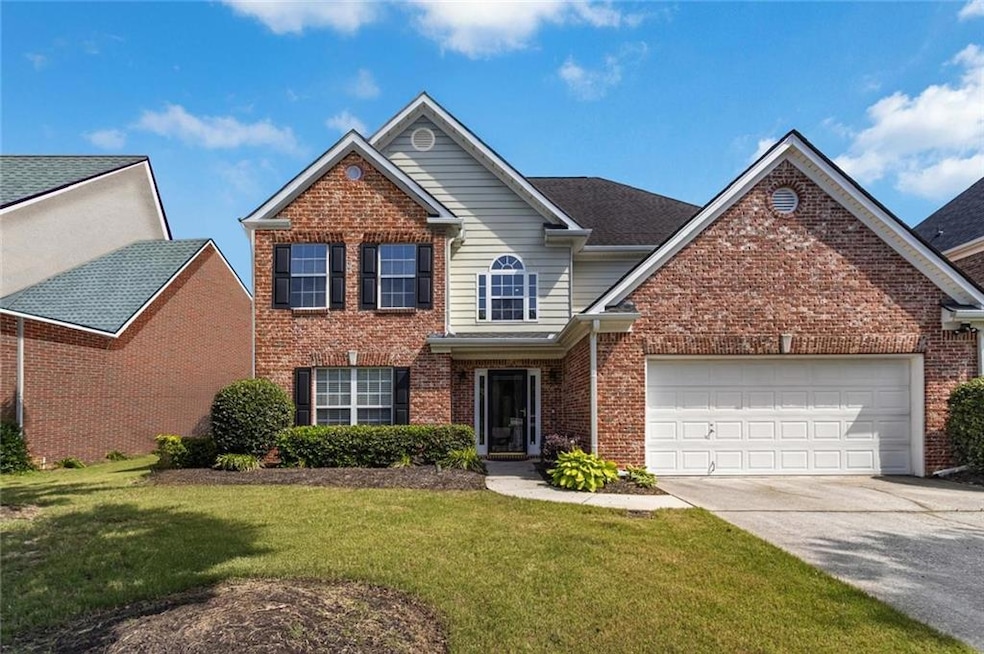 Traditional-style home featuring concrete driveway, brick siding, a garage, and a front lawn