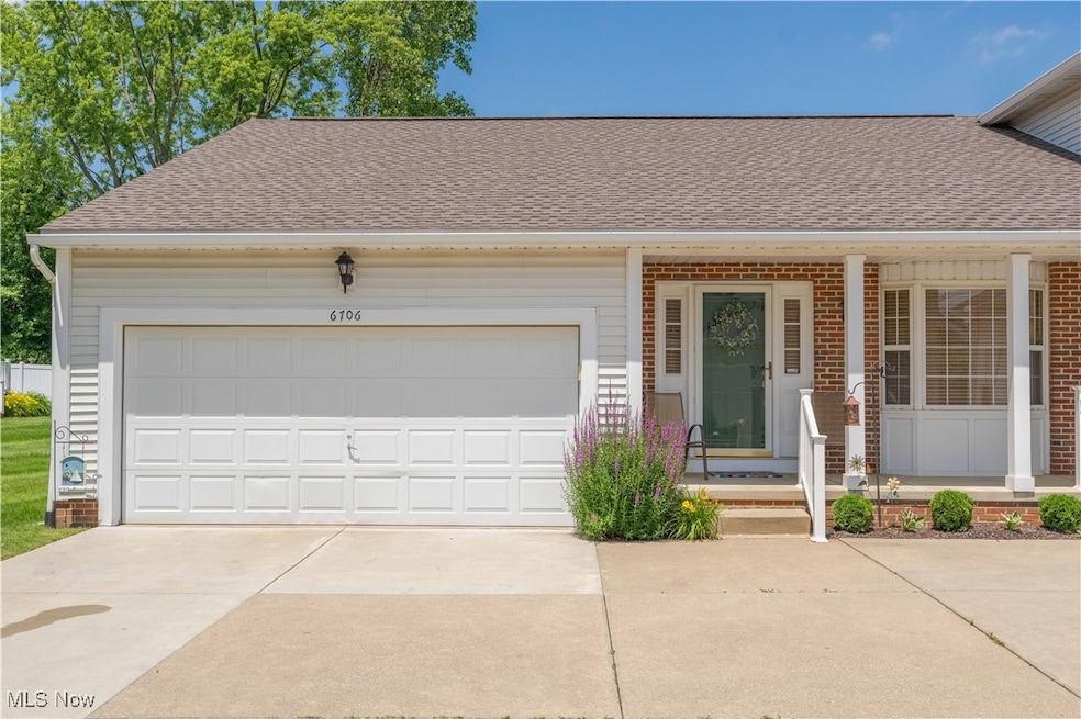 View of front facade with driveway, roof with shingles, brick siding, and an attached garage