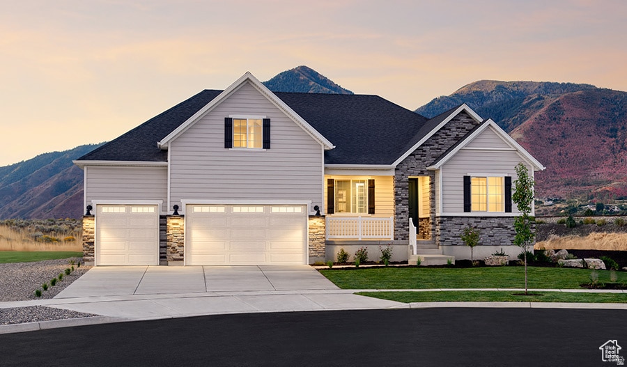 View of front of home featuring a mountain view, covered porch, stone siding, and driveway