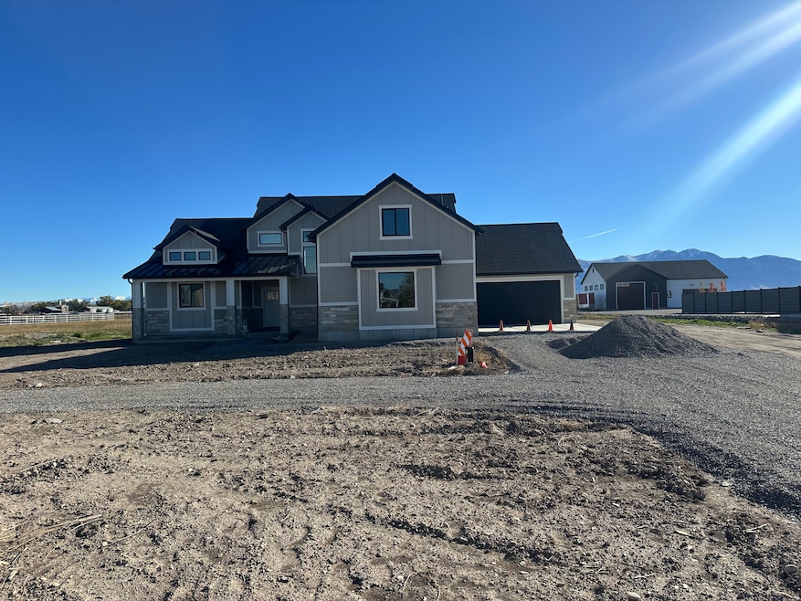 View of front facade featuring stone siding, gravel driveway, a porch, and a garage