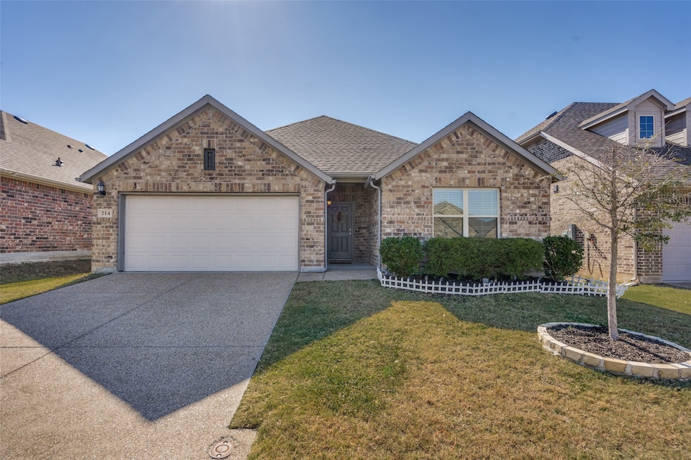 View of front of home with a shingled roof, concrete driveway, brick siding, a front yard, and a garage