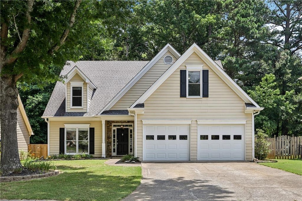 Traditional-style home featuring driveway, roof with shingles, and a garage