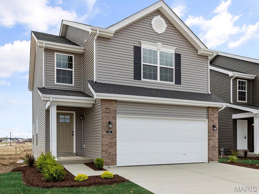 Traditional-style home with concrete driveway, a garage, brick siding, and roof with shingles