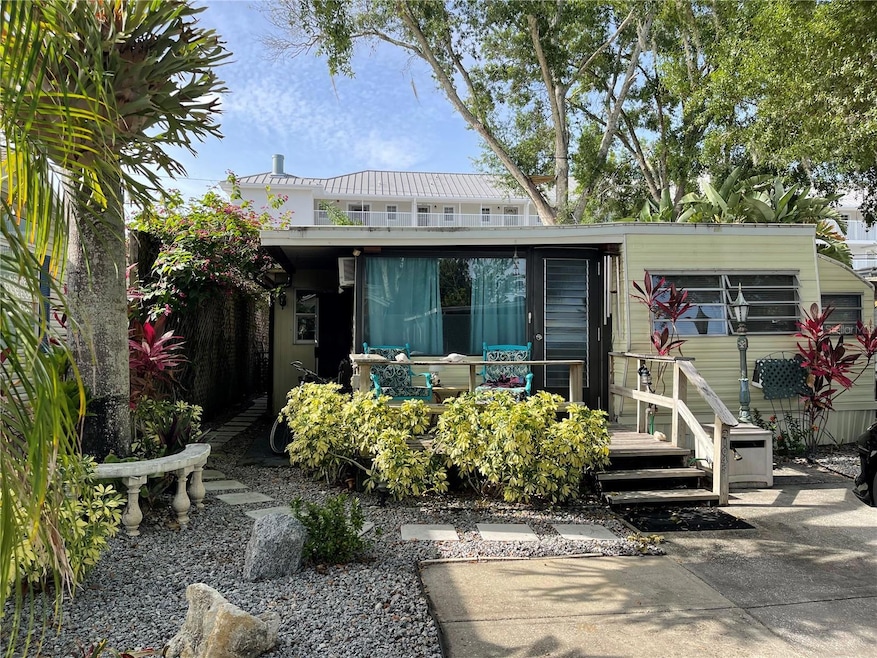 The staghorn fern hanging to the left near the palm tree will convey with the home. Low maintenance yard with crushed granite and concrete parking pad