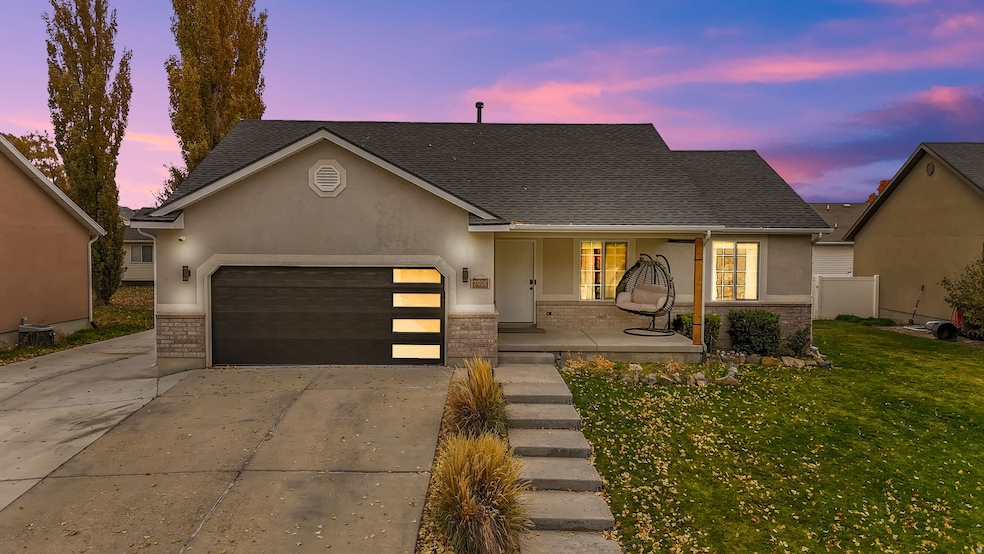 View of front of house featuring covered porch, stucco siding, driveway, and a garage