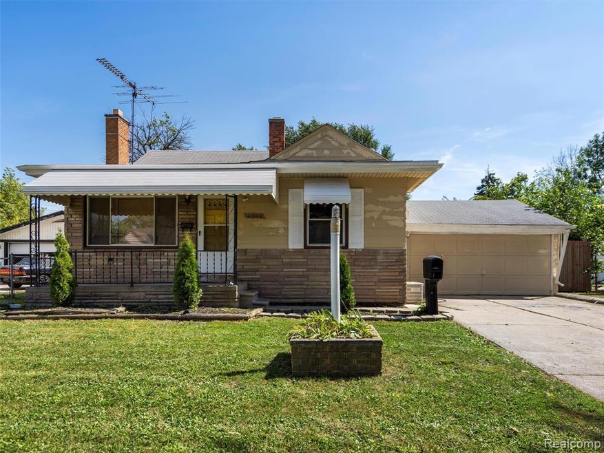 View of front of house with covered porch, a chimney, a front yard, and driveway