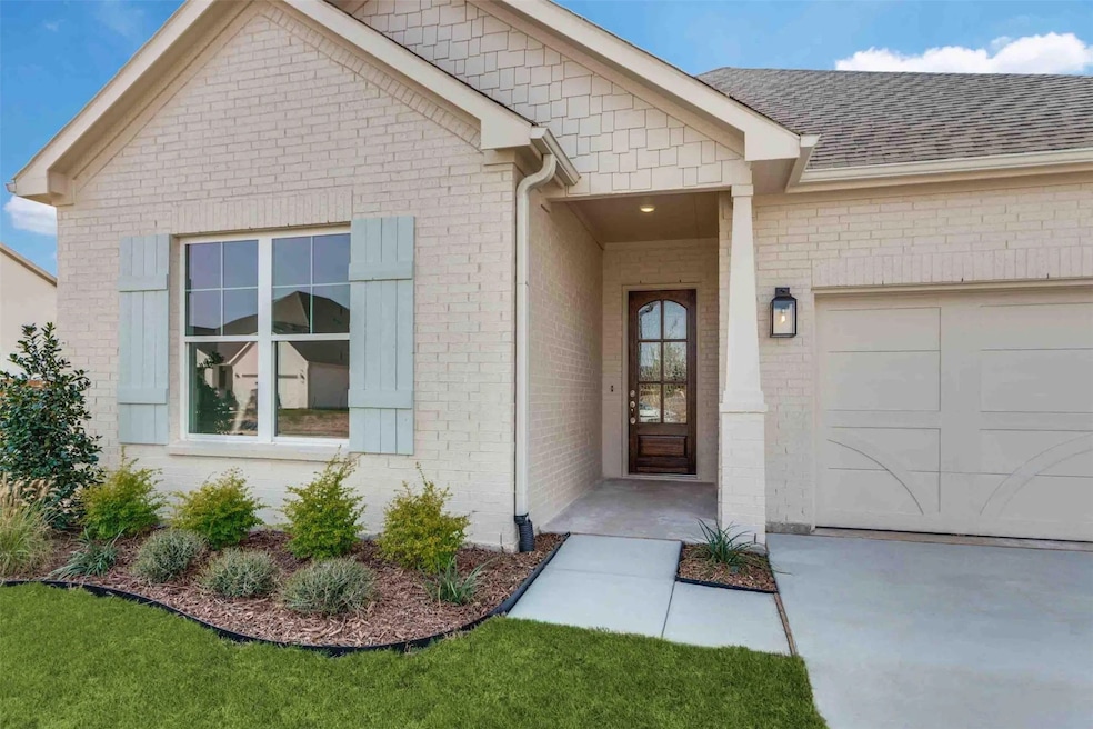 Property entrance with an attached garage, brick siding, and a shingled roof
