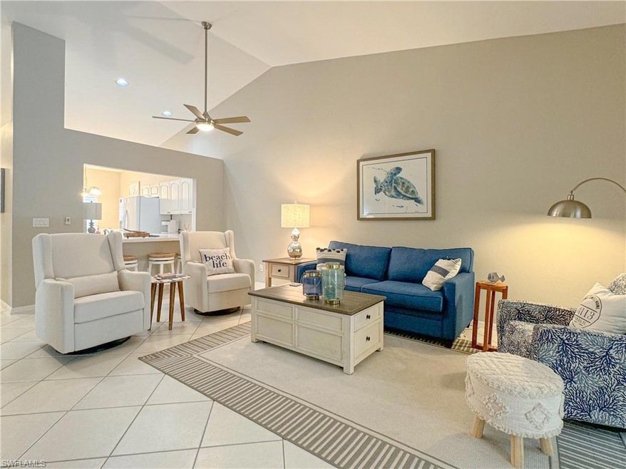 Tiled living room with ceiling fan and vaulted cei