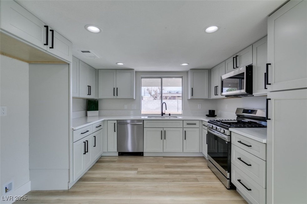 Kitchen with a sink, recessed lighting, light wood
