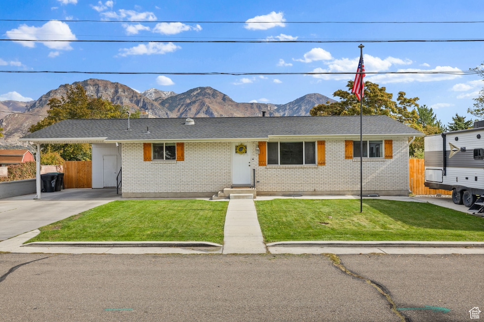 Ranch-style house with a mountain view, a carport, brick siding, and driveway