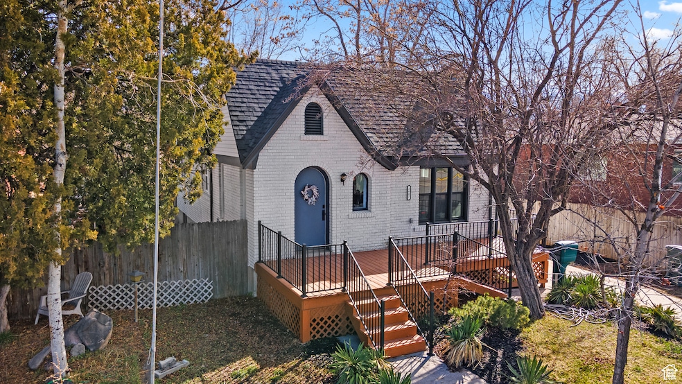 Tudor home with brick siding, a wooden deck, and stairway