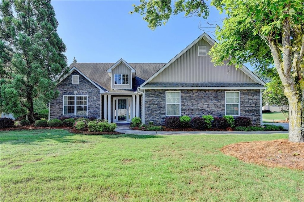 Craftsman-style home with stone siding, a front lawn, and board and batten siding