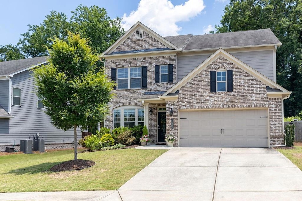 Traditional-style home featuring driveway, a front lawn, brick siding, and an attached garage