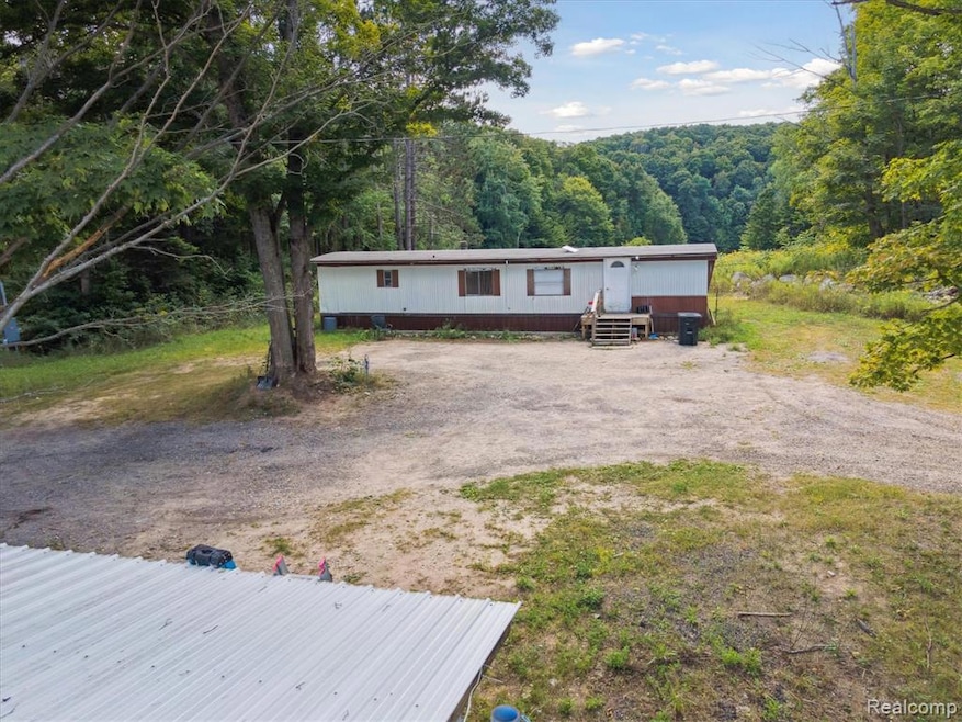 Manufactured / mobile home featuring a forest view and driveway