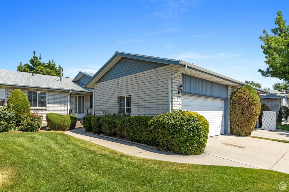 View of front facade featuring driveway, an attached garage, a front yard, and brick siding