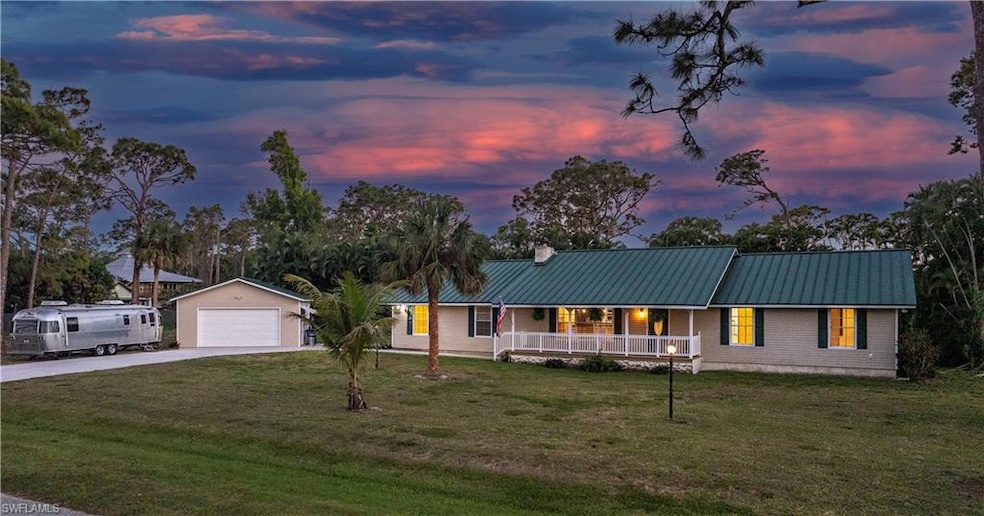 View of front facade with metal roof, a garage, a front lawn, an outdoor structure, and a porch