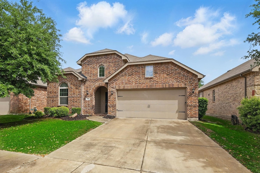 Traditional home with concrete driveway, brick siding, an attached garage, a shingled roof, and a front yard