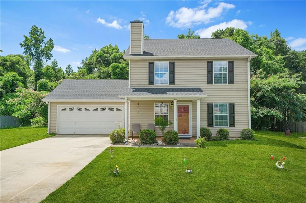 Traditional-style house with an attached garage, concrete driveway, a front lawn, and a chimney