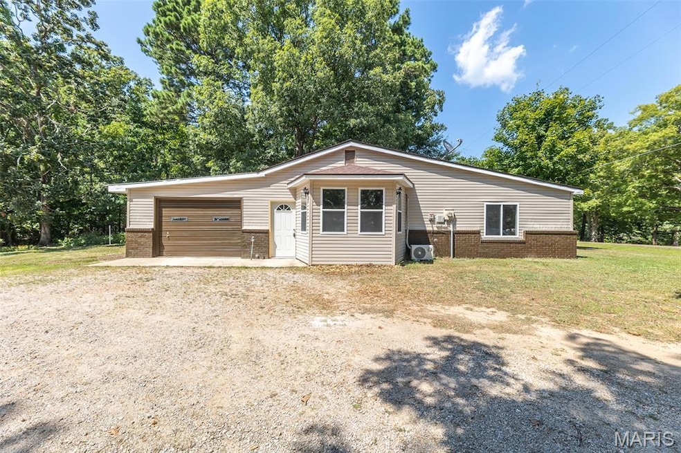 View of front of property featuring brick siding, dirt driveway, and a front lawn