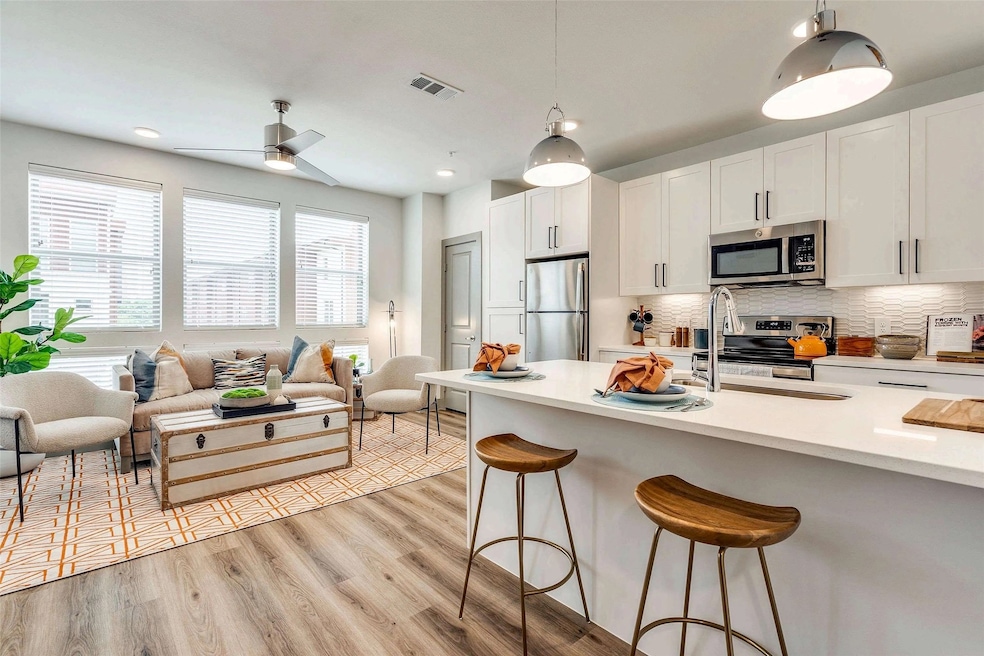 Kitchen with white cabinets, a breakfast bar, stainless steel appliances, backsplash, and recessed lighting