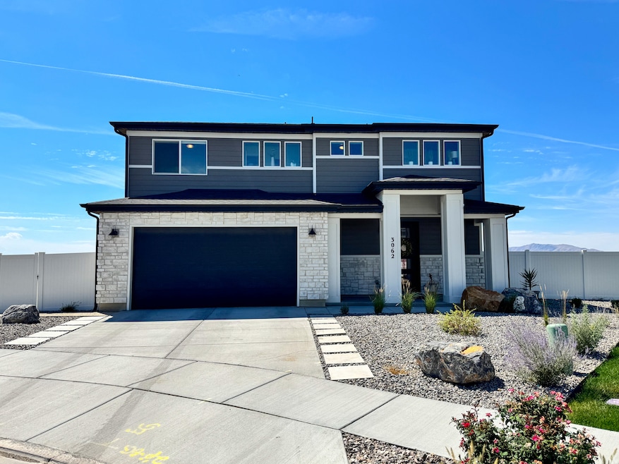View of front of house with stone siding, driveway, and a garage