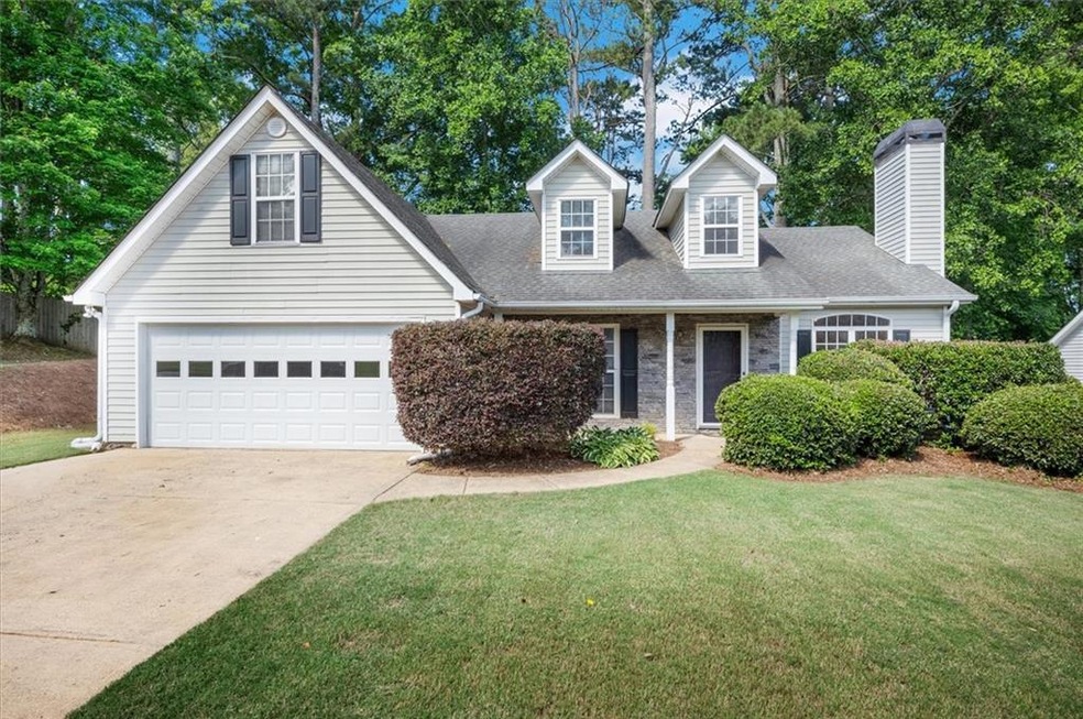 View of front of property featuring driveway, a front lawn, a garage, a chimney, and a shingled roof