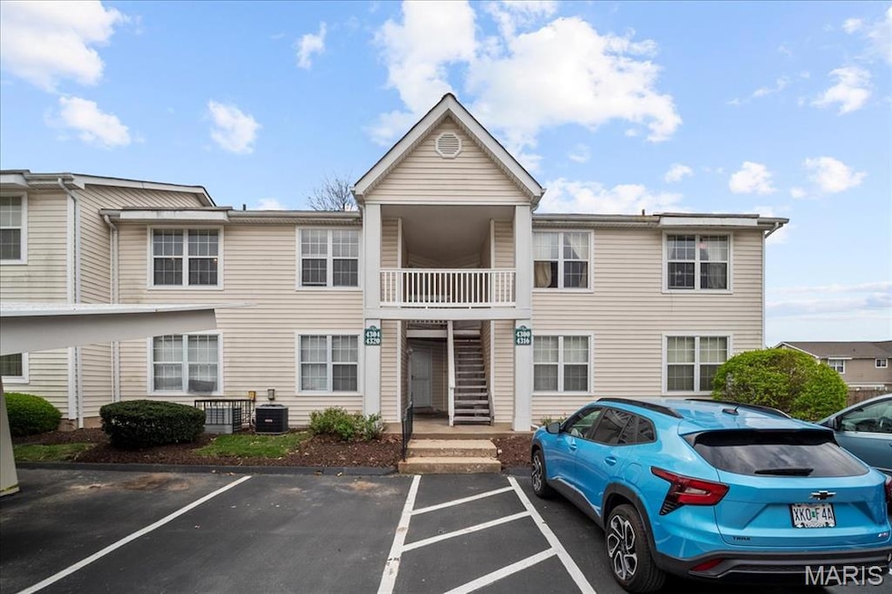 View of building exterior featuring central AC unit and uncovered parking