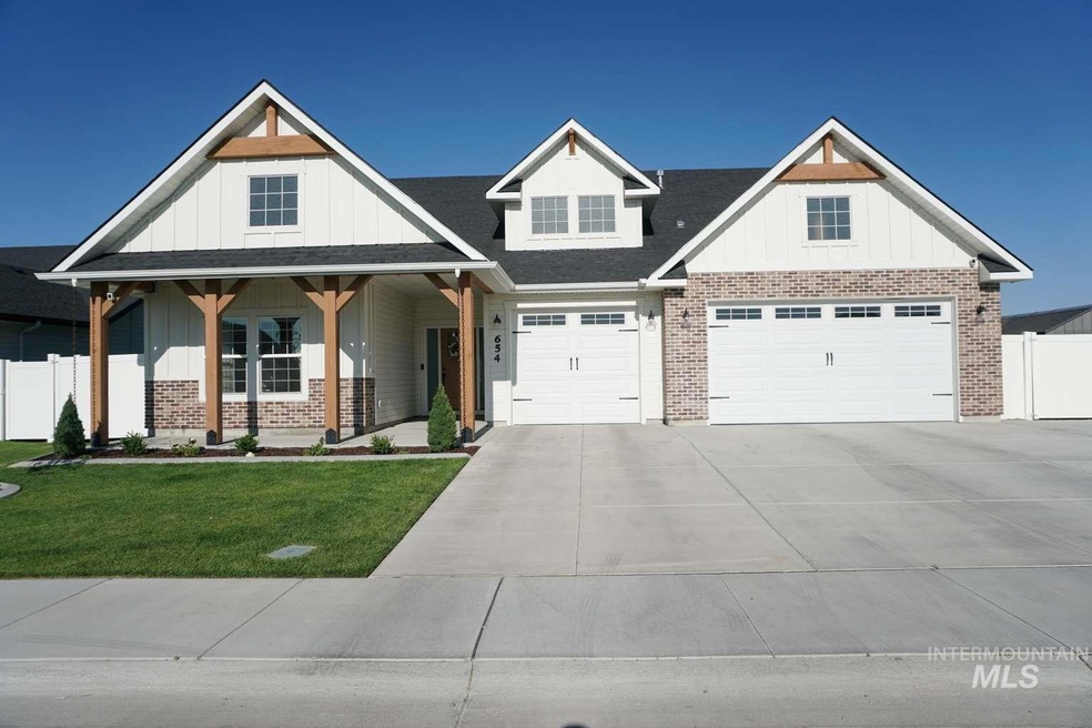 Modern farmhouse with board and batten siding, brick siding, concrete driveway, a porch, and a garage