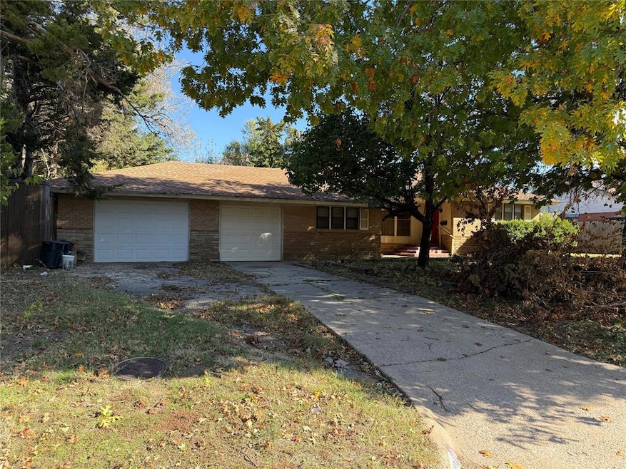 Single story home with brick siding, driveway, and an attached garage