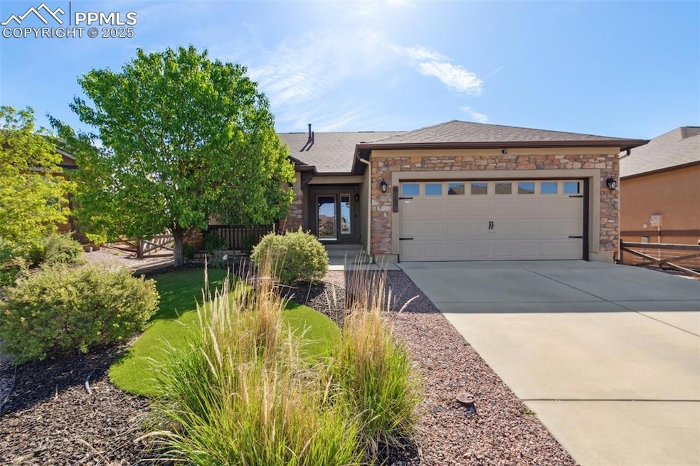 View of front of property featuring stone siding, driveway, and a garage