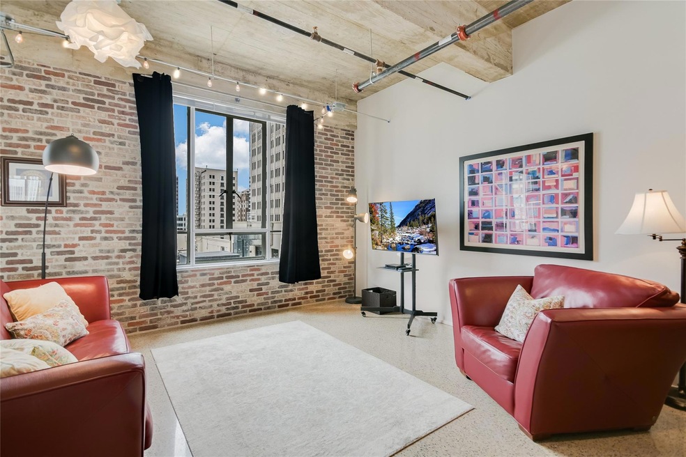 Living area featuring speckled floor and brick wa
