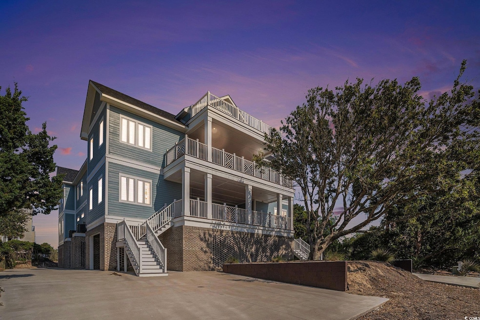 Raised beach house with a balcony, stairs, brick siding, and driveway
