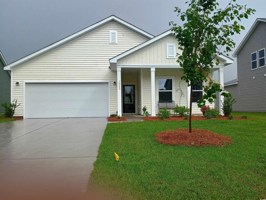 View of front facade featuring a front yard, concrete driveway, a garage, and covered porch