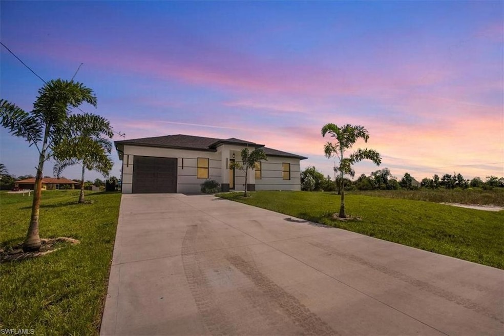 View of front of property featuring concrete driveway, a front yard, and a garage
