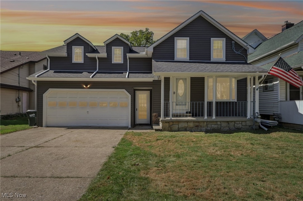 View of front facade featuring driveway, covered porch, a front yard, roof with shingles, and a garage